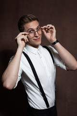 Man in round glasses, suspenders and a white shirt.