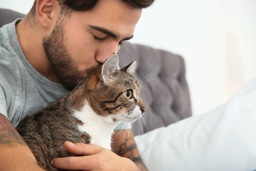Man with cat on bed at home. Friendly pet