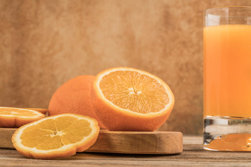 glass of fresh orange juice and oranges on cutting board