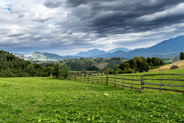 Fototapeta na wymiar A beautiful mountain scenery. Green grass and fenced field