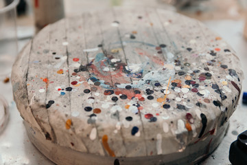 Abstract background in the form of a wooden circle in multi-colored spots from paint and traces of drips from cans.