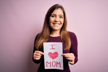 Fototapeta na wymiar Young beautiful woman holding paper with love mom message celebrating mothers day with a happy face standing and smiling with a confident smile showing teeth