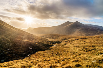 Dramatic sunset with sunrays in beautiful autumn coloured valley with river in Mourne Mountains, highest range in Northern Ireland