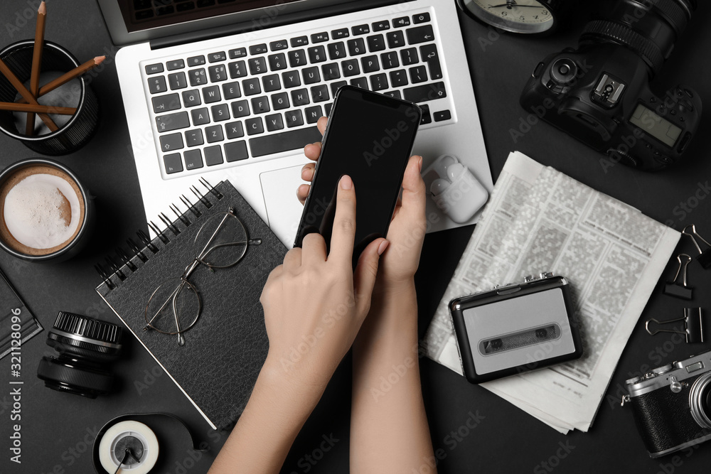 Wall mural journalist with smartphone working at black table, top view