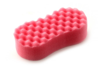 Red sponge for washing dishes on a white background. The sponge has a knurled surface. It can be used for household and car wash.