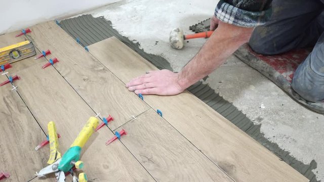 The tiler applies glue and puts the tiles