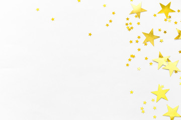Gold confetti and stars and sparkles on a light background. Top view, flat lay. Copy text. Bright and festive background. For Christmas, New Year, Mother's Day.