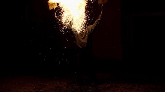 Slow motion of man splashing burning wire wool at night
