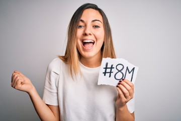 Beautiful woman with blue eyes celebrating 8th march womens day over white background screaming proud and celebrating victory and success very excited, cheering emotion