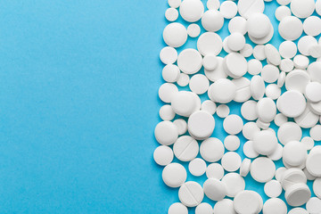 scattered white pills on a blue table. Layout for special offers such as advertising or other ideas. The concept of medicine, pharmacy and healthcare. Space for copy. flat lay for text or logo.