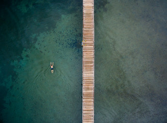A man swim near jetty in the middle of the lake. The picture taken in Matano lake in South Sulawesi, Indonesia.
