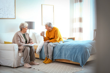 Elderly women spending time together in bedroom. Senior people care
