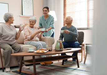 Young woman taking care of elderly people in living room