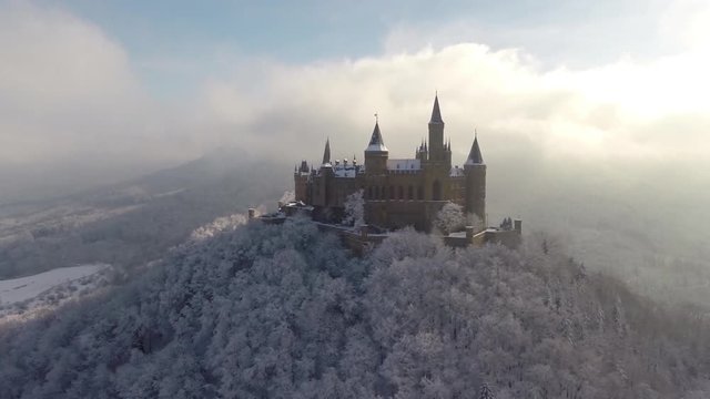 Panning shot of castle on top of mountain surrounded by snow covered trees, Burg Hohenzollern