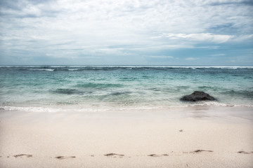 Fototapeta na wymiar Beach with footprints on sand sea surf waves turquoise water blue dramatic sky on horizon landscape 