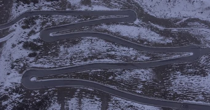 Aerial view of car moving on winding road amidst snow covered mountain, Stelvio Pass, Italy