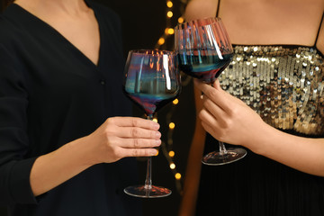 Women clinking glasses of red wine at party, closeup