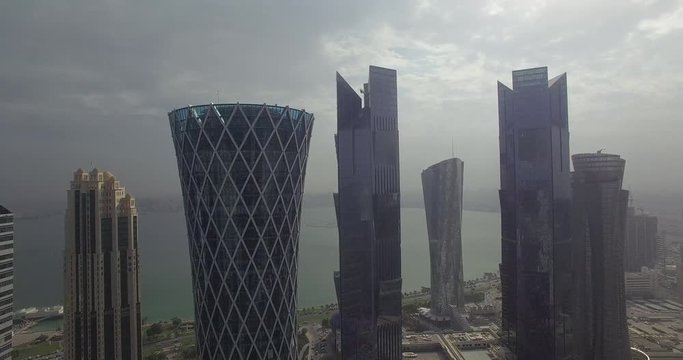Aerial view of skyscrapers by sea against cloudy sky, Doha, Qatar