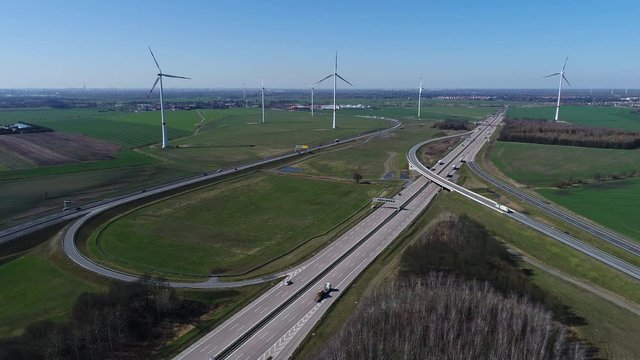 Aerial drone footage of vehicles moving on highways next to fields with wind turbines, Germany