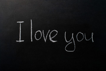 The inscription on the black chalkboard with the chalk "I love you." The inscription in white chalk. Valentine`s day.