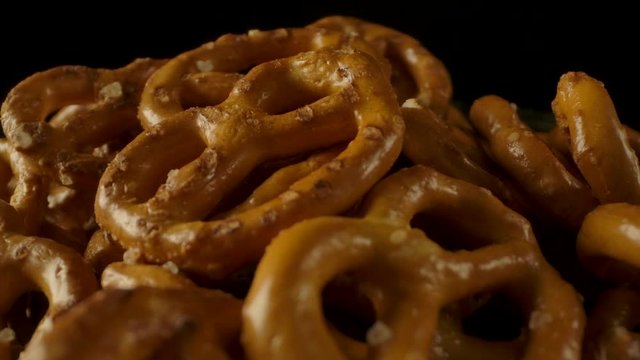 Pan around view of fresh yummy pretzels with salt arranged in pile.