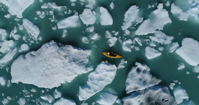 Zoom out shot of woman kayaking between icebergs in water, Alaska, USA