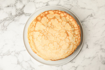Stack of fresh thin pancakes on white marble table, top view