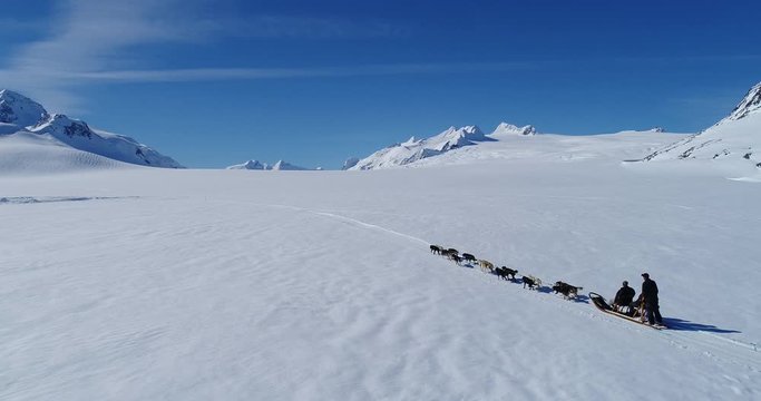 Drone footage of people dogsledding on snowy landscape against sky, Alaska, USA