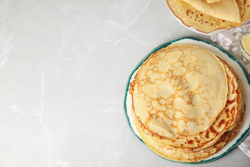 Stack of fresh thin pancakes on light grey marble table. Space for text