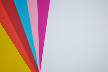 colored papers laid in a fan pattern on a white paper as background photo with copy space