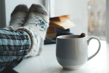 Woman and cup of mulled wine near window indoors, closeup. Winter drink