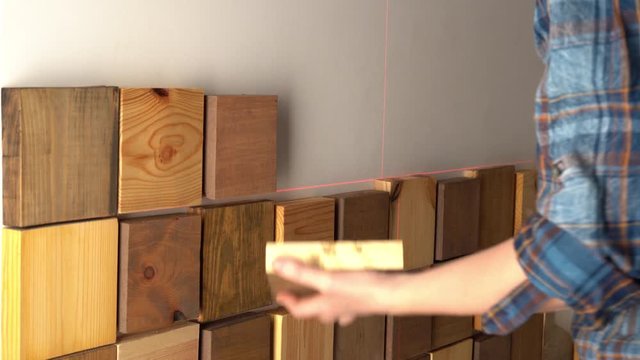 original modern repair in a loft style. woman decorates a wall in an apartment with wooden pieces