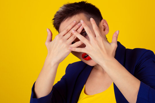 Closeup Scared Woman Covering Face With Hands Hiding Face Looking Peering Peeking Through Fingers On Yellow Background. Family Problems And Woman Violence Cover Face Fight Fear, Afraid, Abused Girl