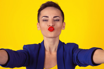 Blowing a kiss, selfie shot. Closeup woman short hair girl puckering lips for a virtual kiss while...