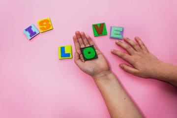 The word IS LOVE. Hands of the child hold letters. Alphabet. Learn letters with a child. ABC