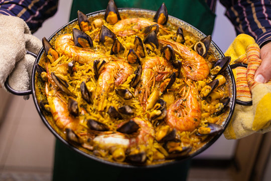 Fideua of seafood with prawns and mussels in paella and cook showing the typical food of Valencia in Spain.