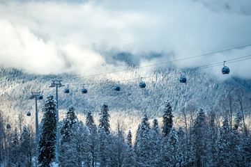 Winter Mountain landscape at the Rosa Khutor ski resort in Sochi, Russia. Cable car cabin over pine...