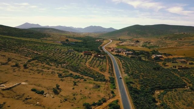 Drone shot of car moving on road amidst houses and field against sky, Sidi Ifni, Morocco