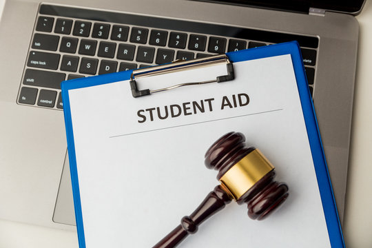 Document with student aid and wooden gavel on the table with laptop isolated