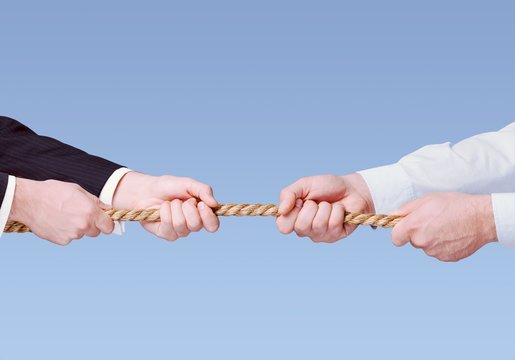 Tug war, two businessman pulling a rope in opposite directions isolated on white background