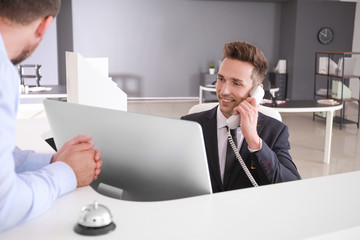 Male receptionist working with visitor in office