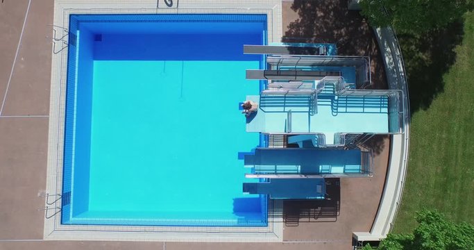 Lockdown shot of man sitting on diving platform over swimming pool, Leonberg, Germany