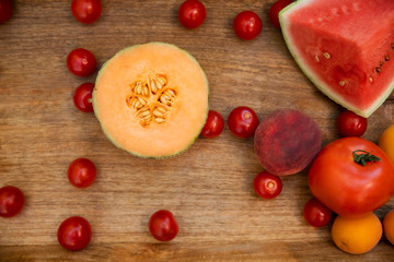 Raw healthy vegetables and fruits on wooden board i rustic style. Red fresh food in vegetarian diet, natural vitamins in summer. Wooden background. Top view and close up.