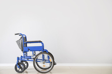 Empty wheelchair near light wall