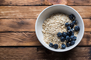 Oatmeal with blueberries in a bowl on a wood background