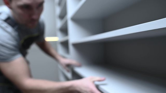 Caucasian Men in His 30s Assembling White Modern Apartment Closet Cabinets.