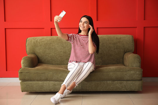 Young Woman Taking Selfie While Sitting On Sofa At Home