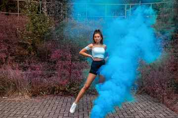 Young girl posing with colored smoke in an abandoned place