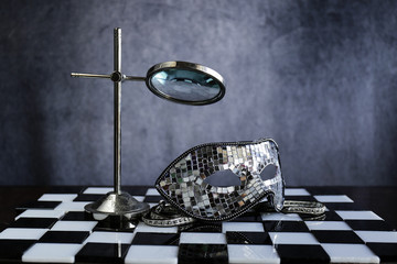 Maschera d'argento sopra la scacchiera bianca e nera ,la festa dei coriandoli e cristalli