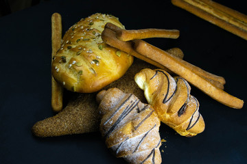 Different kinds of fresh bread with grain on black rustic background.